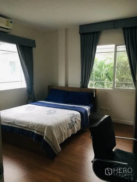 Detached House for rent in Bang Kapi, Bangkok - Bedroom with double bed, wood flooring, air conditioner and corner windows facing the garden.