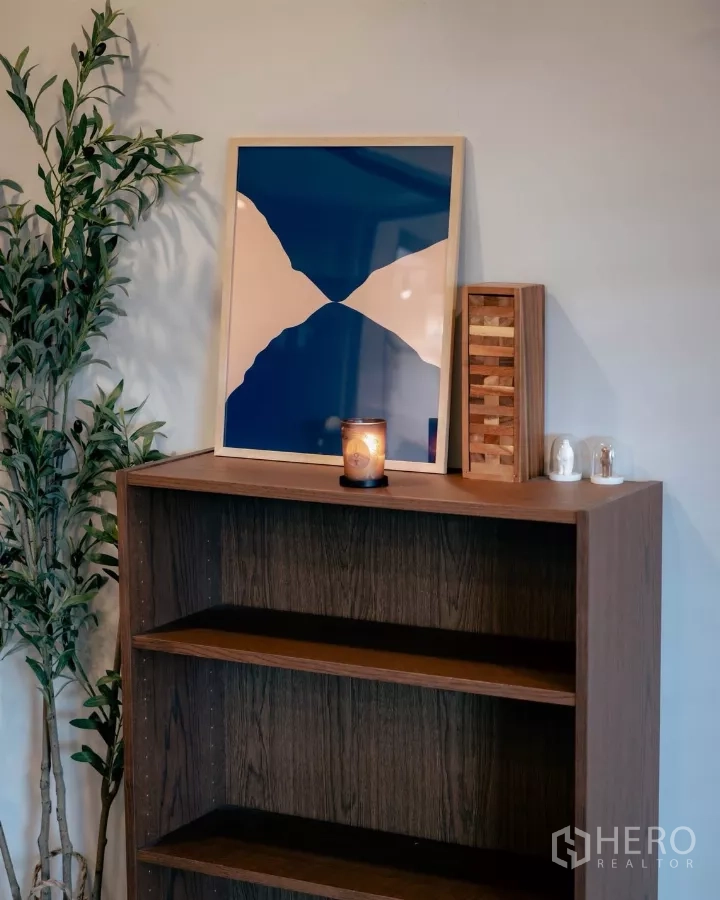 Detached House for rent or sale in Bang Phli, Samut Prakan - Close‑up of wooden bookshelf styled with artwork and a candle.