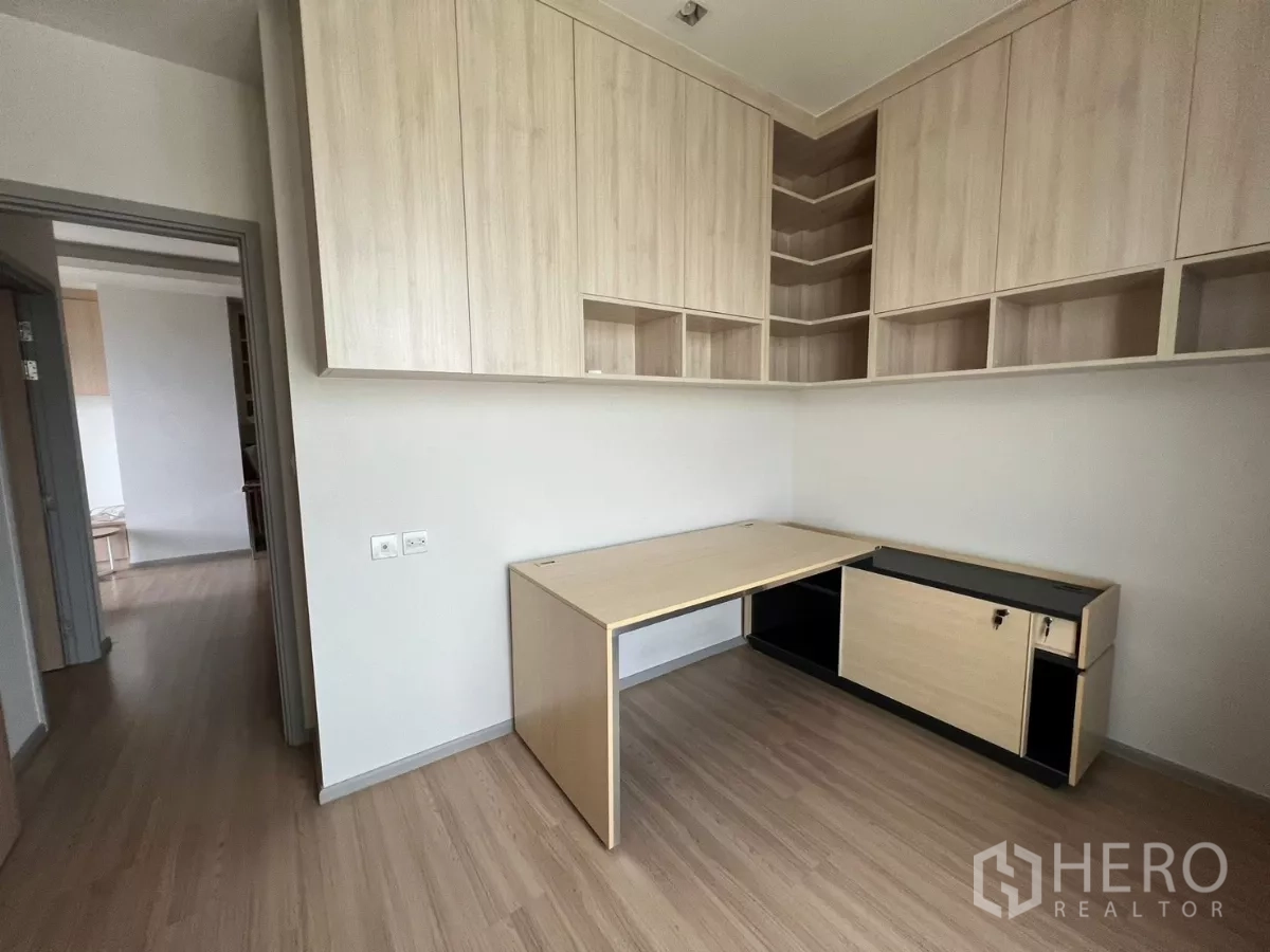 Condominium for rent or sale in Chatuchak, Bangkok - Corner view of the second bedroom showing extensive wall cabinets and an L‑shaped desk.
