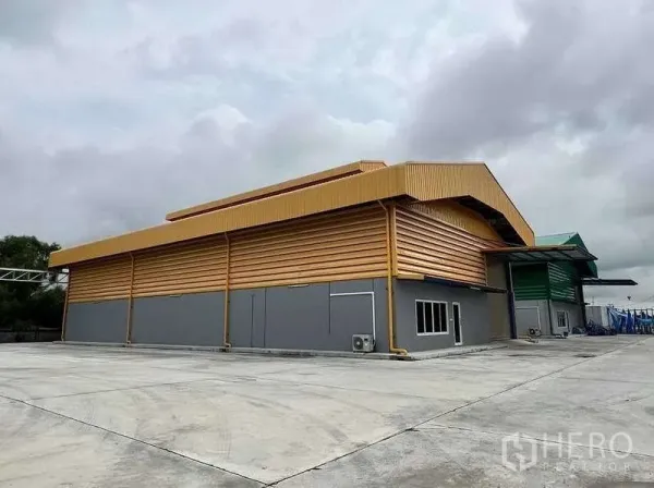คลังสินค้า ให้เช่าในLat Lum Kaeo, Pathum Thani - มุมด้านข้างของโกดังโลหะ พร้อมถนนภายในกว้างและกำแพงรั้ว.