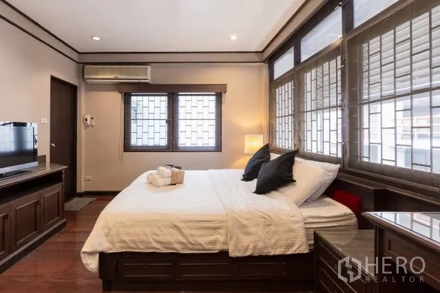 Detached House for rent in Watthana, Bangkok - Primary bedroom with double bed, TV console and wraparound windows.