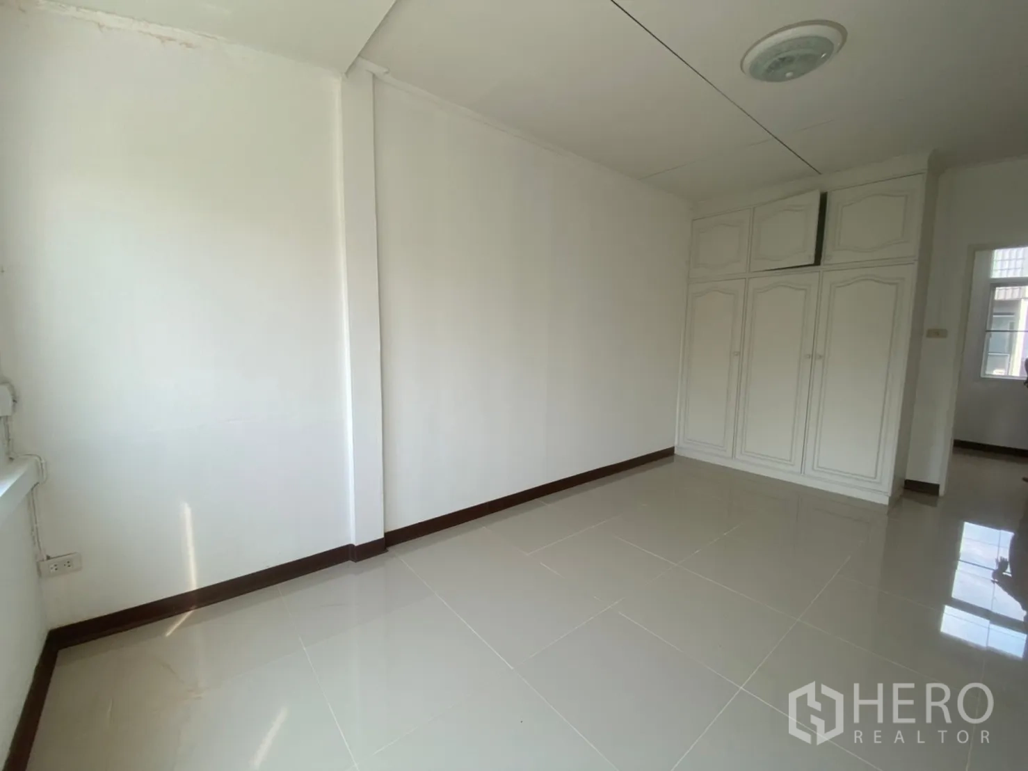 Townhouse for rent in Watthana, Bangkok - Bedroom with built-in wardrobe and glossy tiled flooring.
