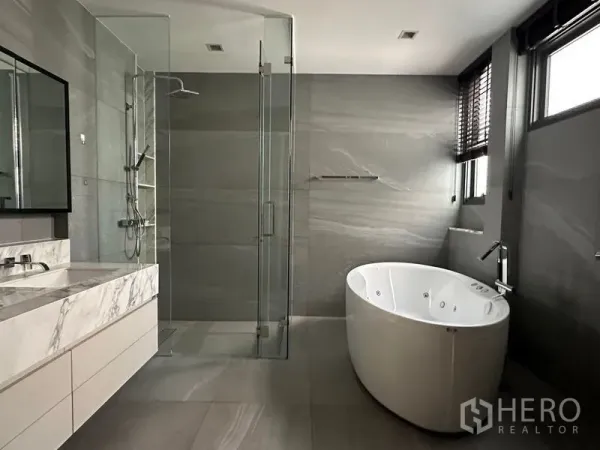 Detached House for rent in Phra Khanong, Bangkok - Luxury bathroom with glass rain shower, round jacuzzi tub, and marble vanity.