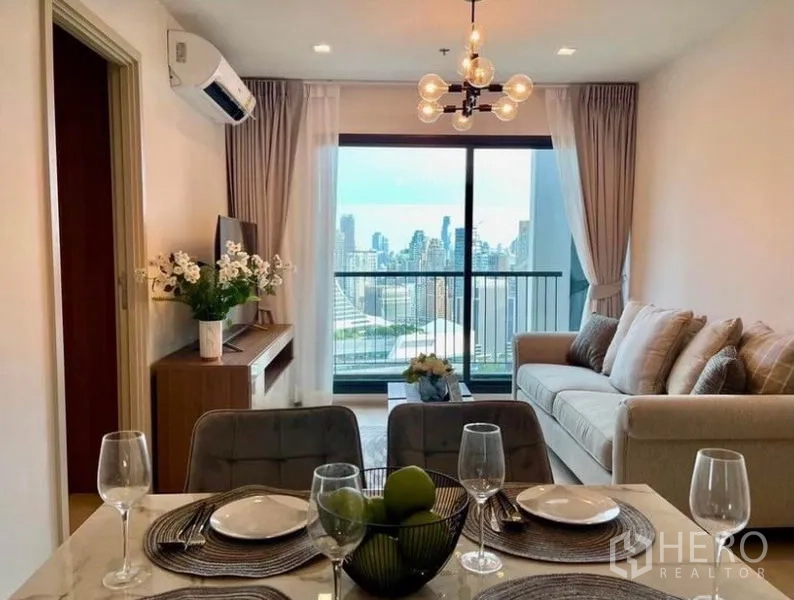 คอนโด ให้เช่าในPathum Wan, Bangkok - โต๊ะทานอาหารสำหรับสี่ที่นั่ง มองเห็นห้องนั่งเล่นสว่างและระเบียงวิวกรุงเทพฯ