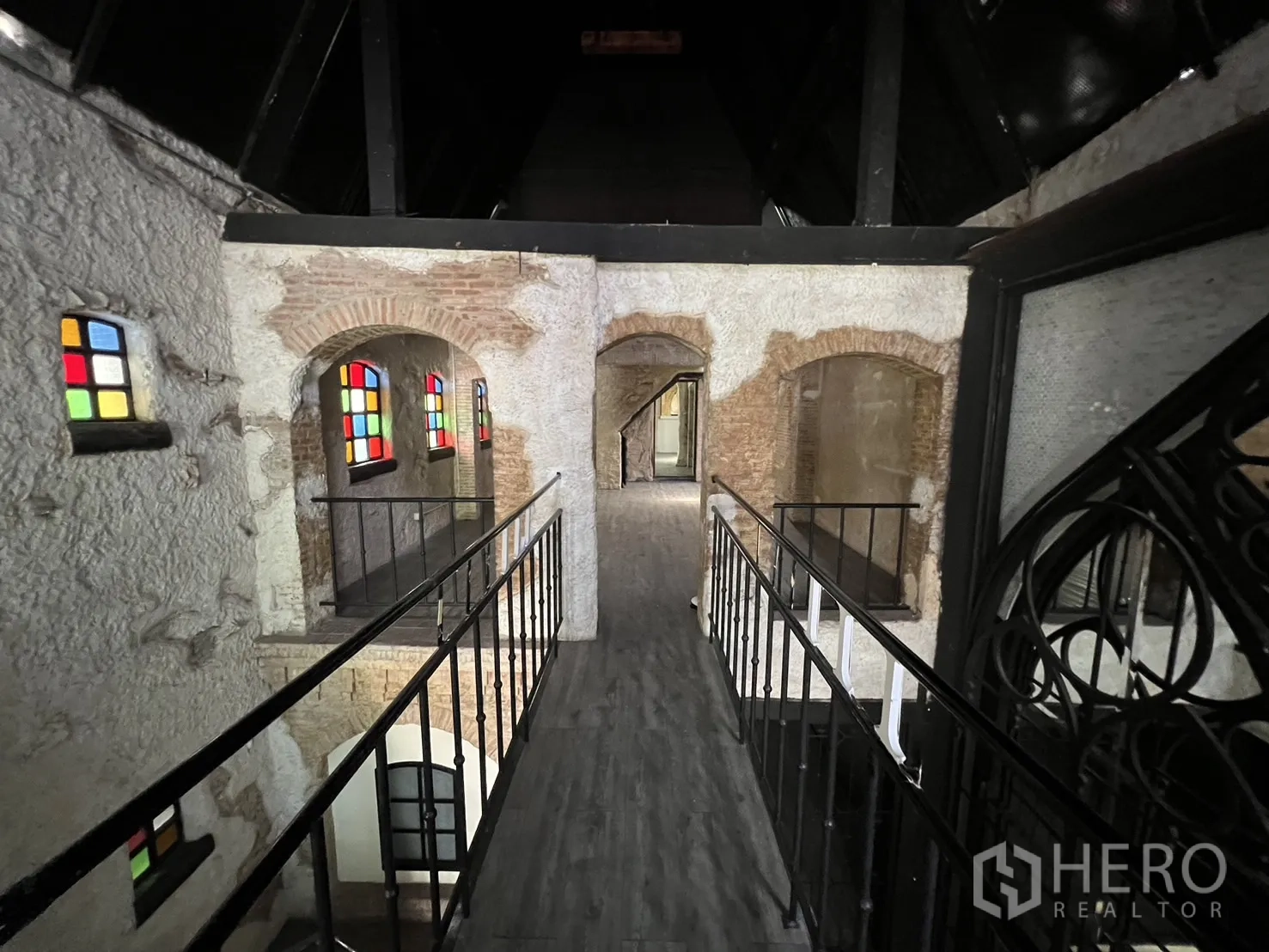 Retail Space for rent in Watthana, Bangkok - Mezzanine walkway with metal railings overlooking arched brick openings and stained-glass details.