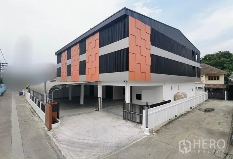 Warehouse for rent in Samut Prakan - Modern three‑storey warehouse in Bang Na, Bangkok with bold orange and black facade, gated driveway and wide access.