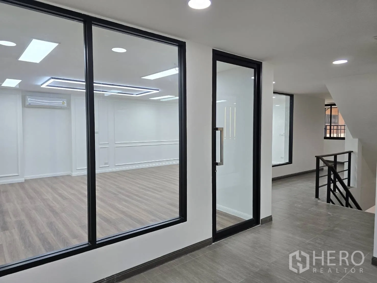 Home Office for rent in Chatuchak, Bangkok - Corridor with glass partitions and a door opening to a large meeting or work area.