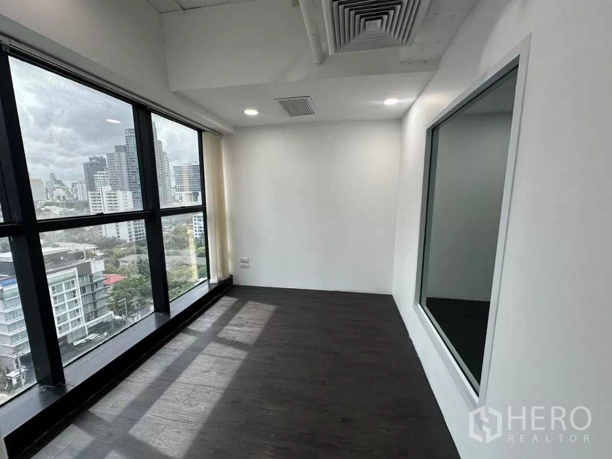 Office Space for rent in Watthana, Bangkok - Compact office with large exterior window and interior viewing window to meeting space.