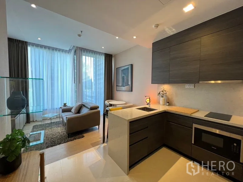 公寓 出租在Watthana, Bangkok - 开放式厨房，深色橱柜与石英台面，面向采光充足的客厅。