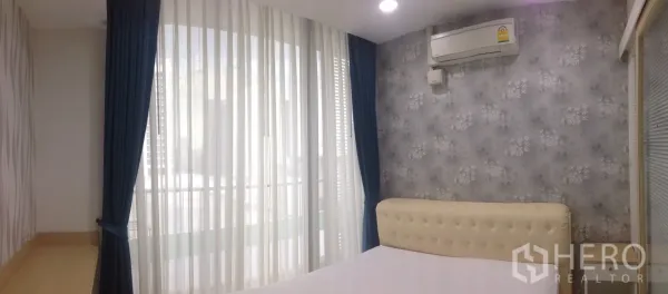 Condominium for rent in Phaya Thai, Bangkok - Cozy bedroom with upholstered headboard, gray floral wallpaper and floor-to-ceiling curtains.