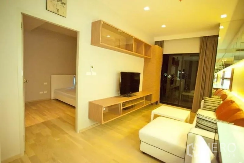 คอนโด ให้เช่าหรือขายในWatthana, Bangkok - ห้องนั่งเล่นสว่างพร้อมโซฟา L-Shape ชั้นวางทีวี พื้นไม้ และวิวระเบียง ประตูห้องนอนเปิดอยู่