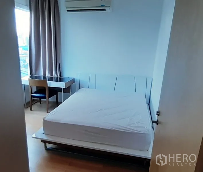 Condominium for rent in Khlong Toei, Bangkok - Cozy bedroom featuring a bed, study desk by the window, and wall-mounted air conditioner.