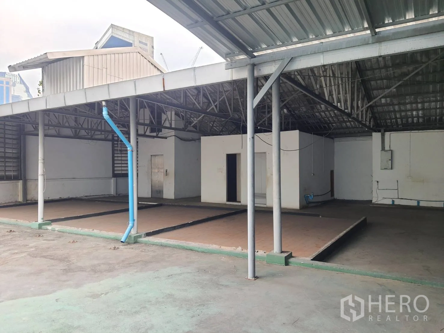 Shophouse for rent in Khlong Toei, Bangkok - Covered semi-outdoor bay with metal roof, raised platforms and visible utilities in a Bangkok shophouse.