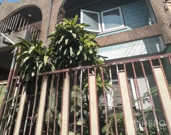联排别墅 出售 - 联排别墅两层外立面，拱形阳台与开启窗，绿植繁茂，前方金属栅栏。