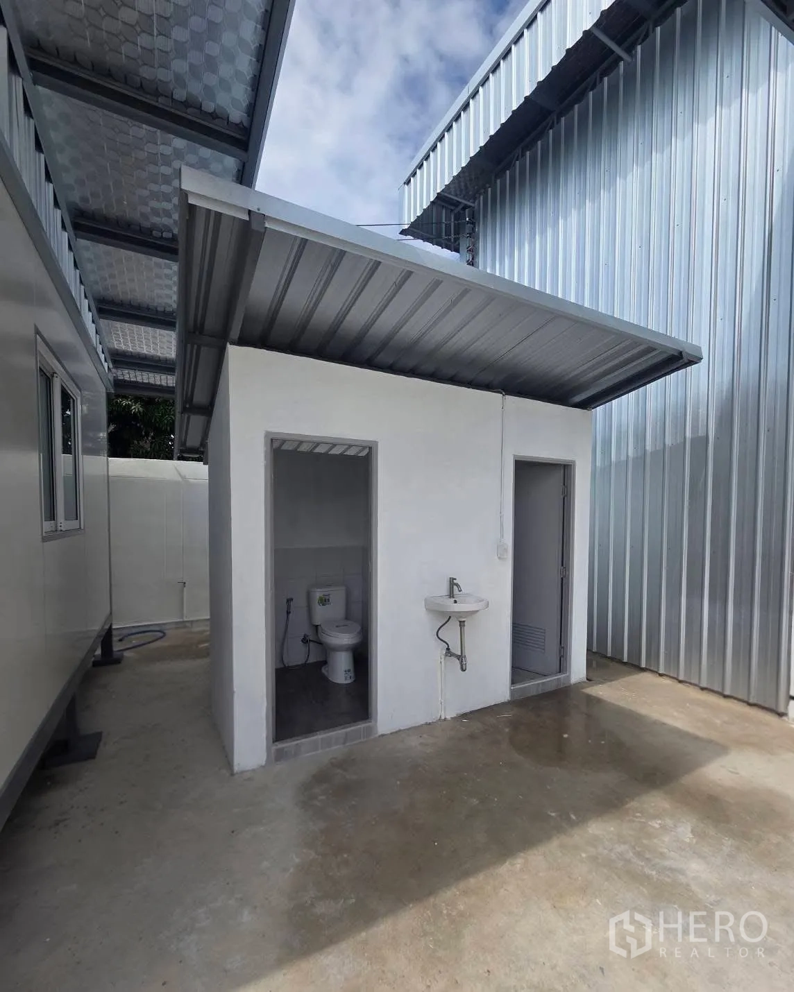 Factory for rent in Mueang Samut Prakan, Samut Prakan - Separate restroom block with toilet, sink, and covered roof.