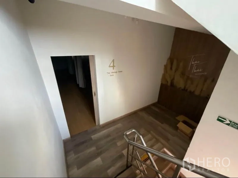 Shophouse for rent in Khlong Toei, Bangkok - Staircase landing leading to Thai massage rooms with a wooden accent wall.