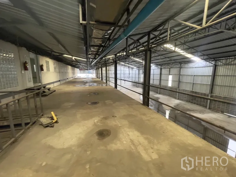 Warehouse for rent in Prawet, Bangkok - Metal-roofed mezzanine walkway with exposed service pipes in the warehouse.