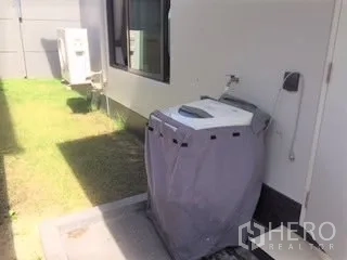Detached House for rent in Bang Kapi, Bangkok - Outdoor utility area with washing machine beside the house and small lawn.