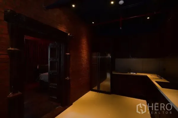 公寓 出租或出售在Khlong Toei, Bangkok - L形厨房，深色柜体、不锈钢冰箱与红砖特色墙。