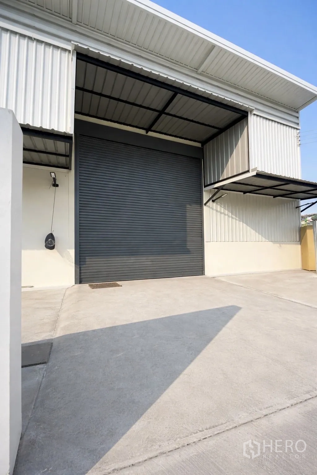 Warehouse for rent in Prawet, Bangkok - Loading area with an oversized roller shutter door and covered awning.