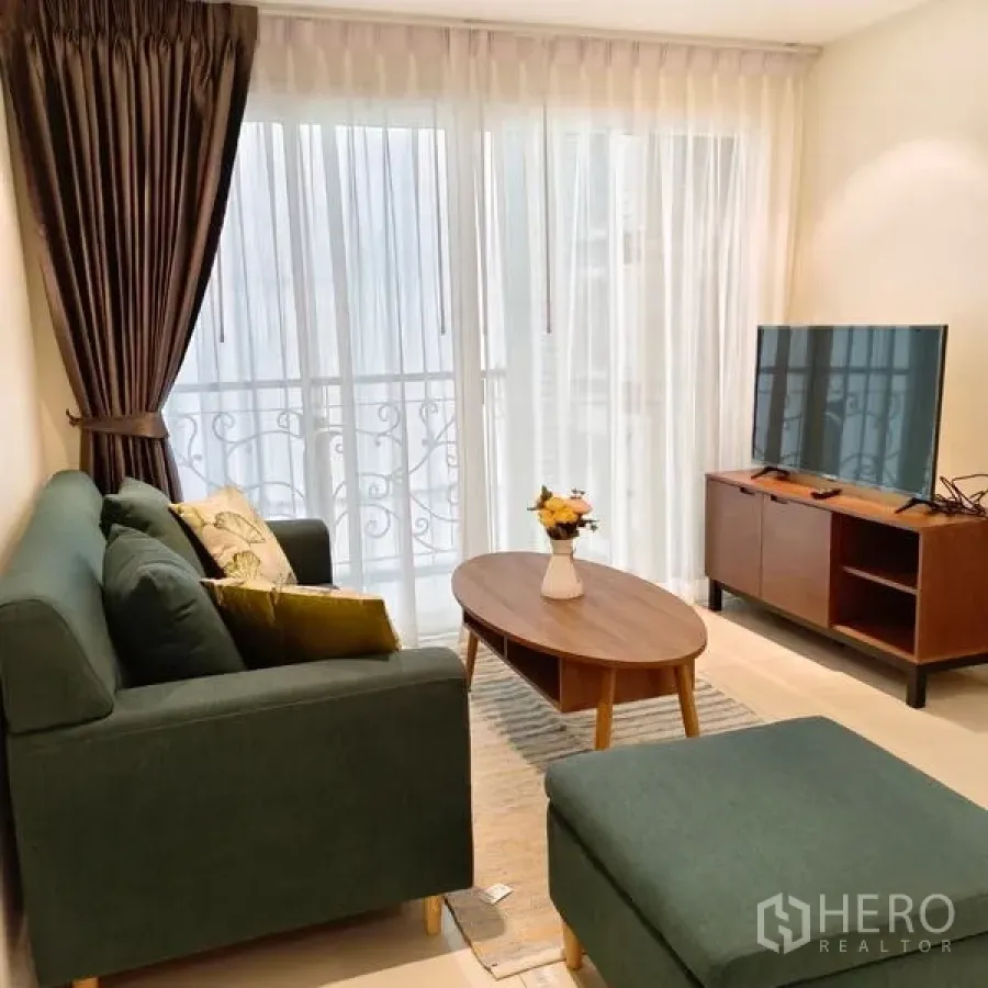 คอนโด ให้เช่าในWatthana, Bangkok - มุมมองห้องนั่งเล่นอีกด้าน เห็นราวระเบียง โต๊ะกลางทรงวงรี และชั้นวางทีวี ในคอนโดเขตวัฒนา