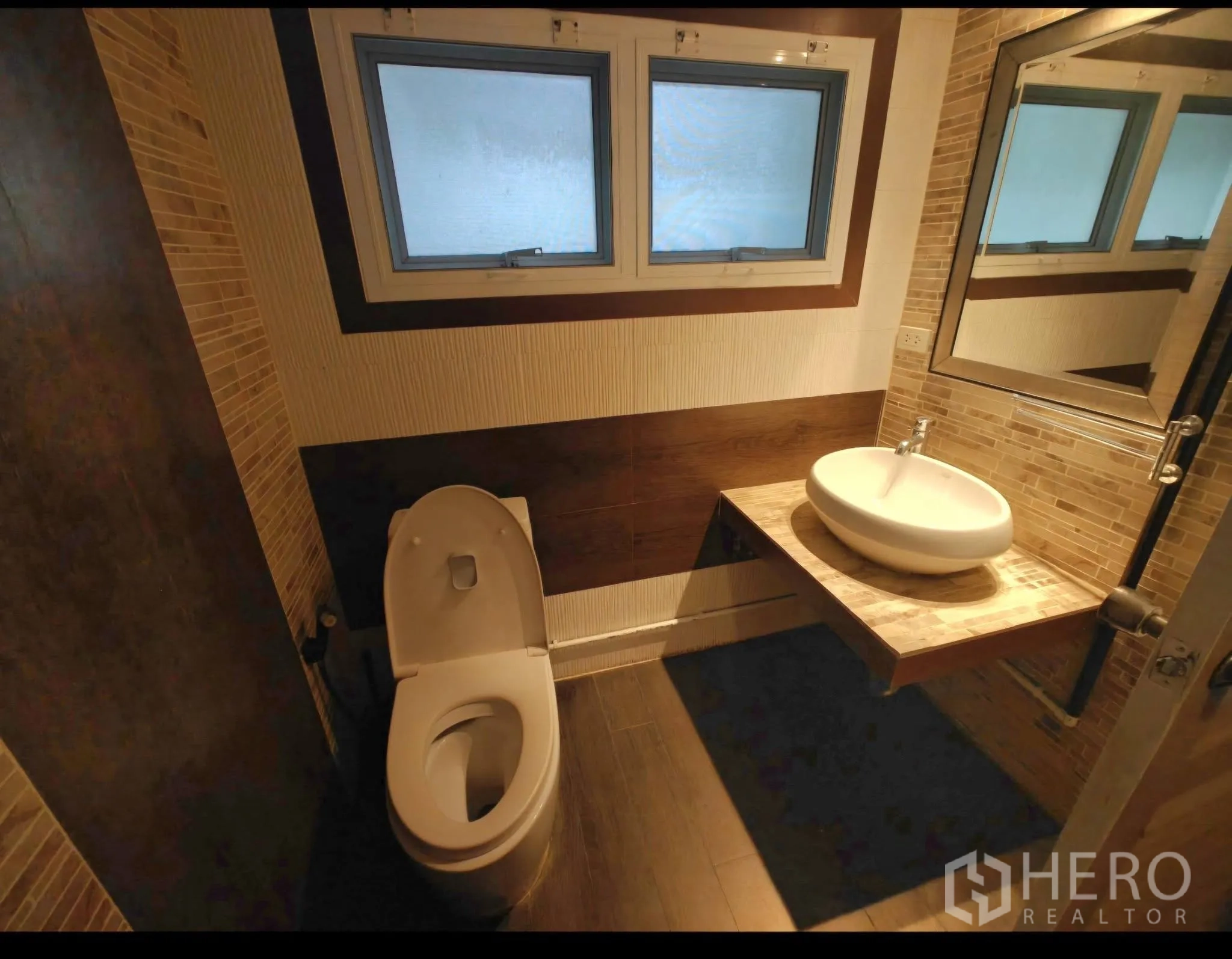 公寓 for rent in Sathon, Bangkok - 卫浴设台上盆、悬空台面、磨砂窗与暖色瓷砖。