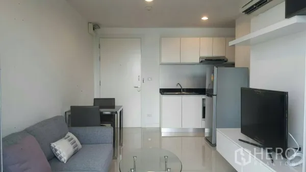 Condominium for rent in Phaya Thai, Bangkok - Full view of living and dining for two with the entry door beside sleek white kitchen cabinets.