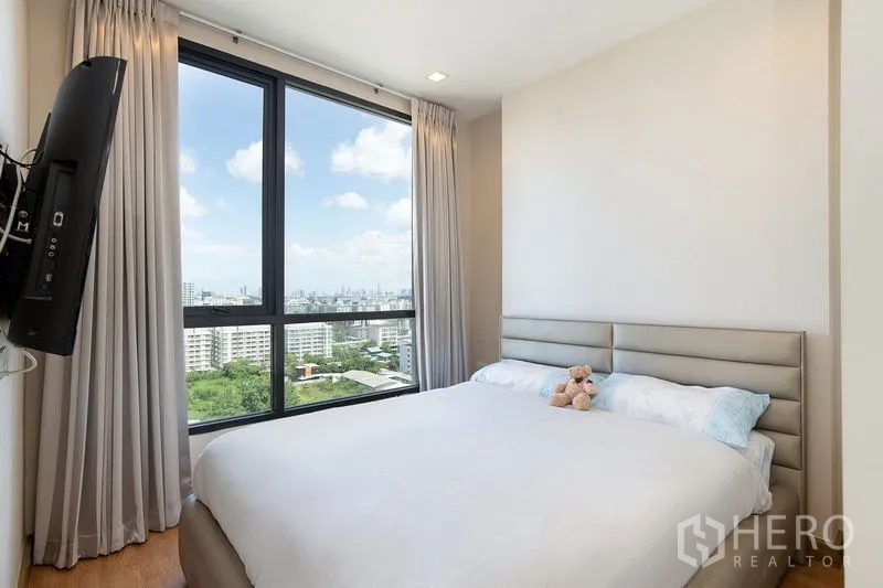 公寓 出租在Watthana, Bangkok - 次卧设大窗与窗帘，开阔城市景观，位于瓦他那区公寓。