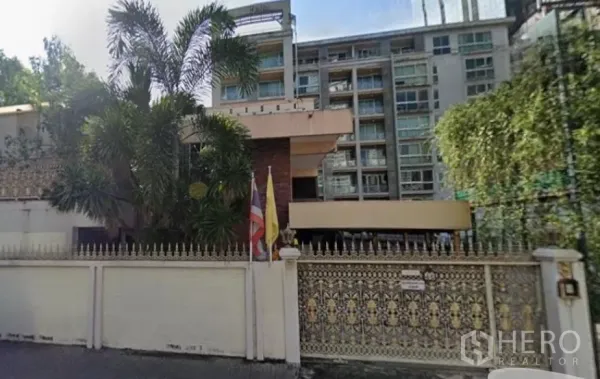 独立式住宅 出售在Khlong Toei, Bangkok - 空堤区带精美铁艺大门的独栋住宅，热带绿化环绕，背景为中高层建筑。