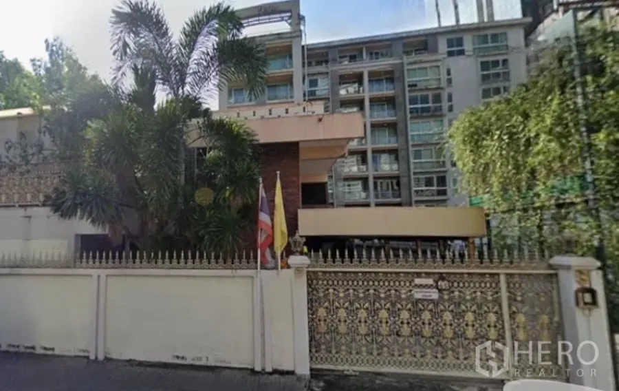 独立式住宅 出售在Khlong Toei, Bangkok - 空堤区带精美铁艺大门的独栋住宅，热带绿化环绕，背景为中高层建筑。
