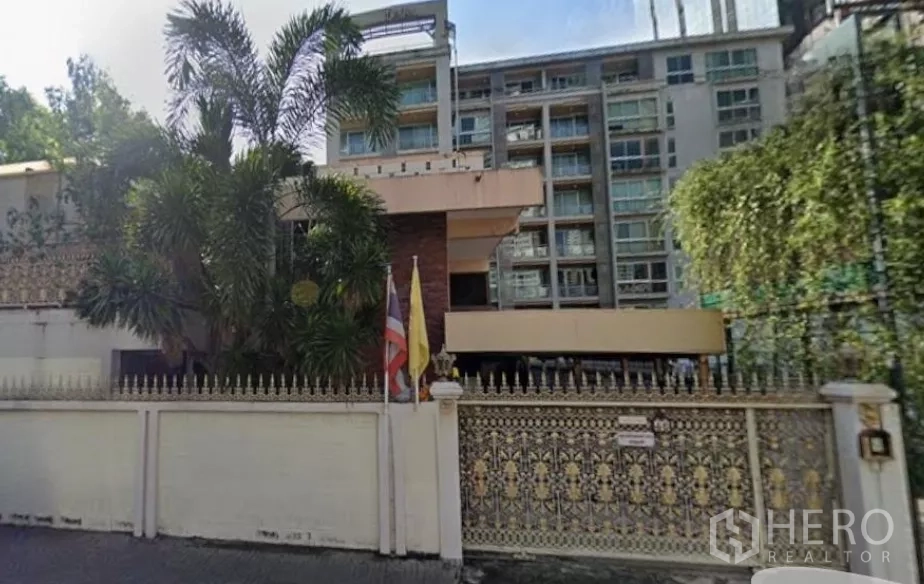 独立式住宅 出售在Khlong Toei, Bangkok - 空堤区带精美铁艺大门的独栋住宅，热带绿化环绕，背景为中高层建筑。