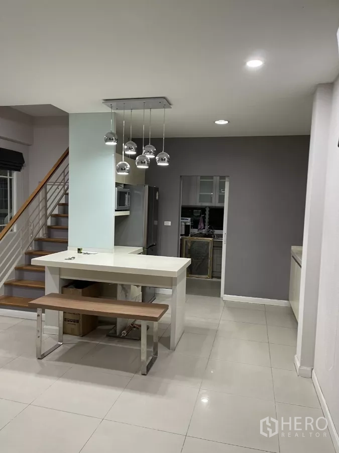 Detached House for rent in Bang Kapi, Bangkok - White kitchen island with bench seating leading toward a pantry area.