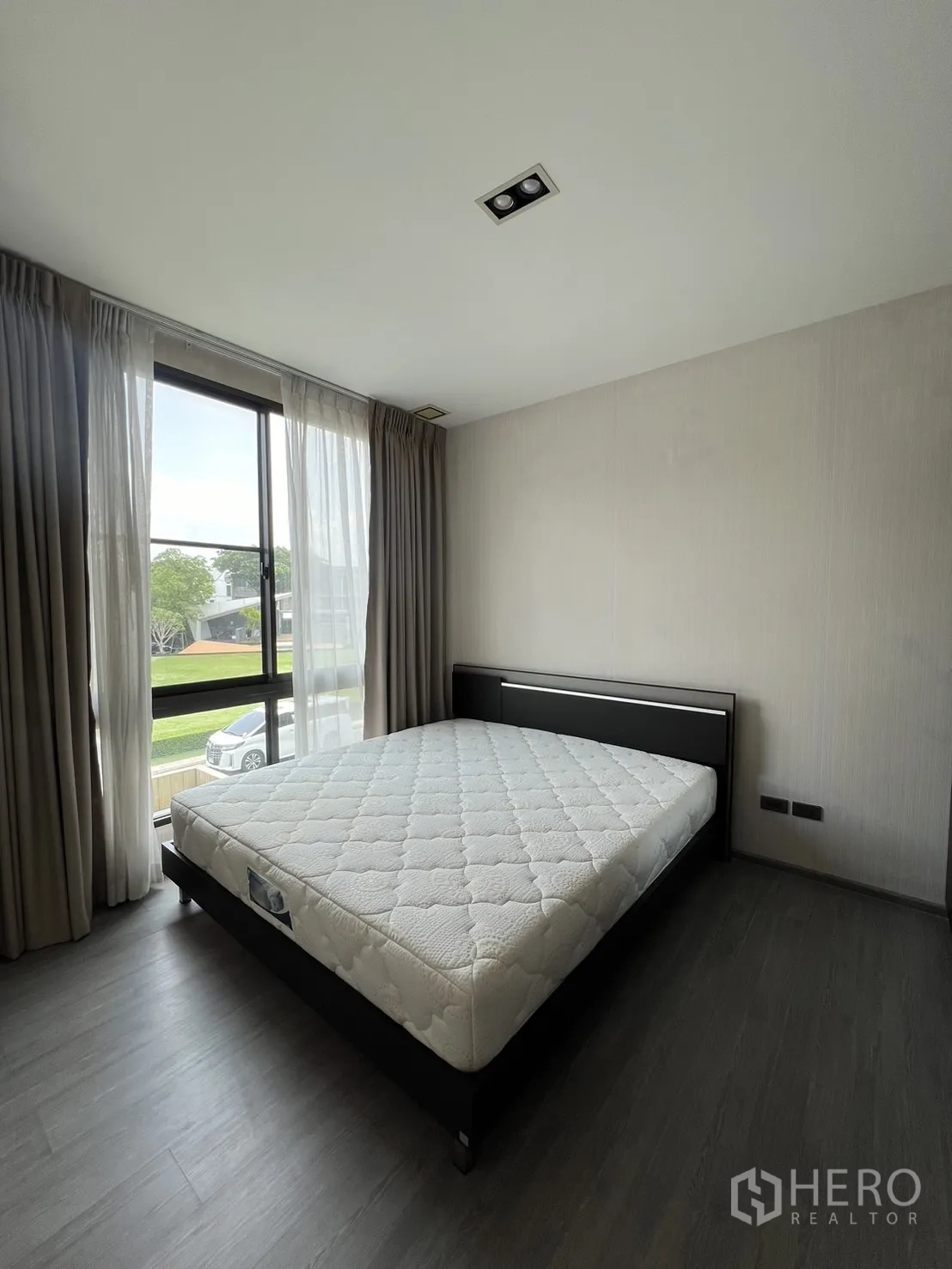 Townhouse for rent in Lat Phrao, Bangkok - Minimal master bedroom with large window, curtains and wood-style floor.
