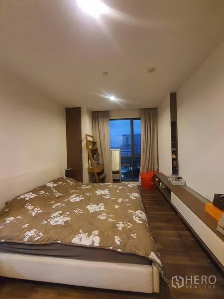 คอนโด ขายในBangkok - ห้องนอนเตียงคู่ พื้นไม้ และหน้าต่างสูงจรดเพดานเชื่อมระเบียงชมวิวเมือง