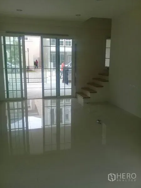 Home Office for rent in Bang Na, Bangkok - Bright ground-floor space with glossy tile flooring, large sliding glass doors, and stairs to upper levels.