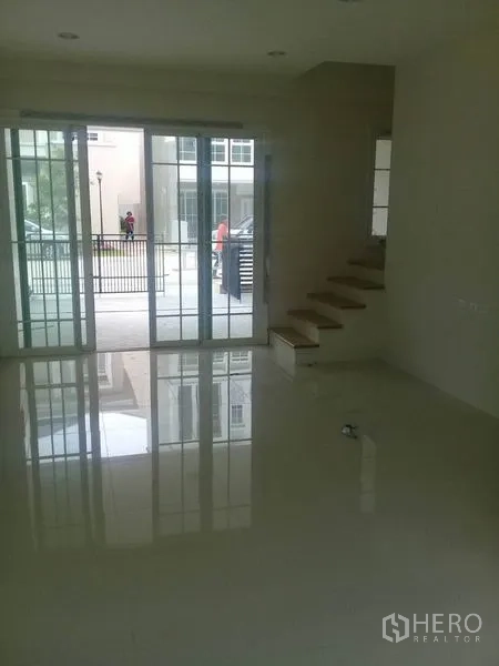 Home Office for rent in Bang Na, Bangkok - Bright ground-floor space with glossy tile flooring, large sliding glass doors, and stairs to upper levels.