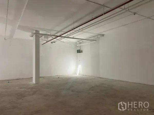 Retail Space for rent - Open‑plan retail floor with high ceiling, exposed services and a central column.