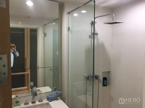公寓 出租在Watthana, Bangkok - 现代浴室，玻璃隔断雨淋花洒与大镜面台盆。