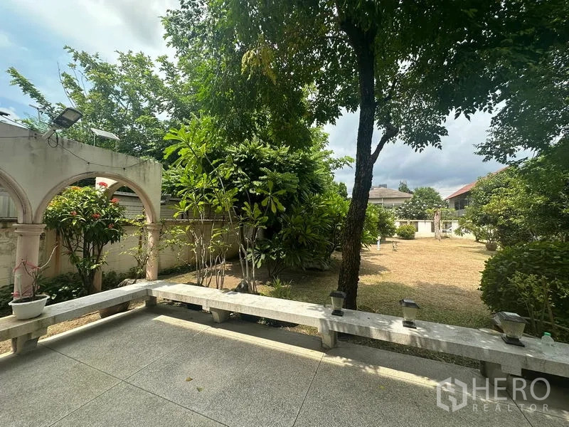 Detached House for sale in Phra Khanong, Bangkok - Shaded patio with concrete benches, arched wall features and lush plants.