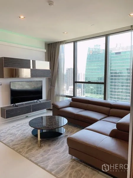Condominium for sale - Lounge with TV wall unit and skyline backdrop of Sathorn offices.