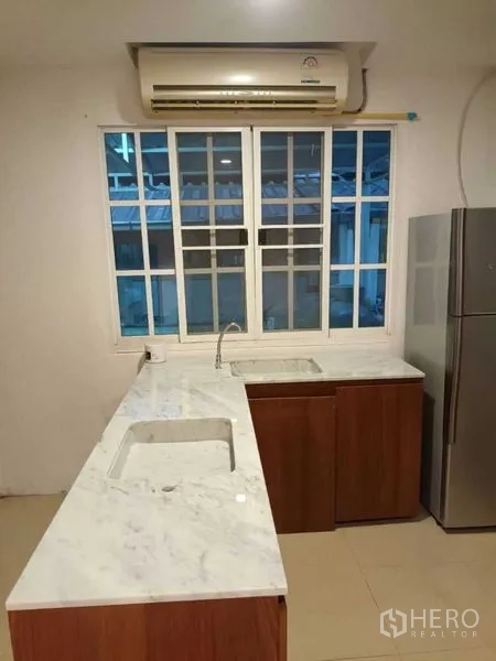联排别墅 出租在Bang Kapi, Bangkok - 采光良好的L型厨房，大理石台面与水槽、窗户