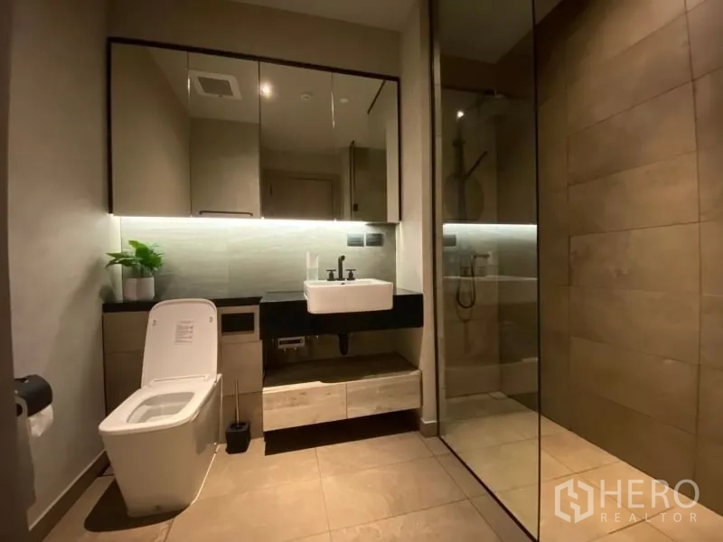 Condominium for rent or sale in Watthana, Bangkok - Contemporary bathroom with large mirrored cabinets, vanity, and glass‑enclosed rain shower.