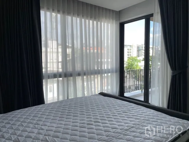 独栋房屋 for rent in Watthana, Bangkok - 转角卧室，落地纱帘与阳台景观。