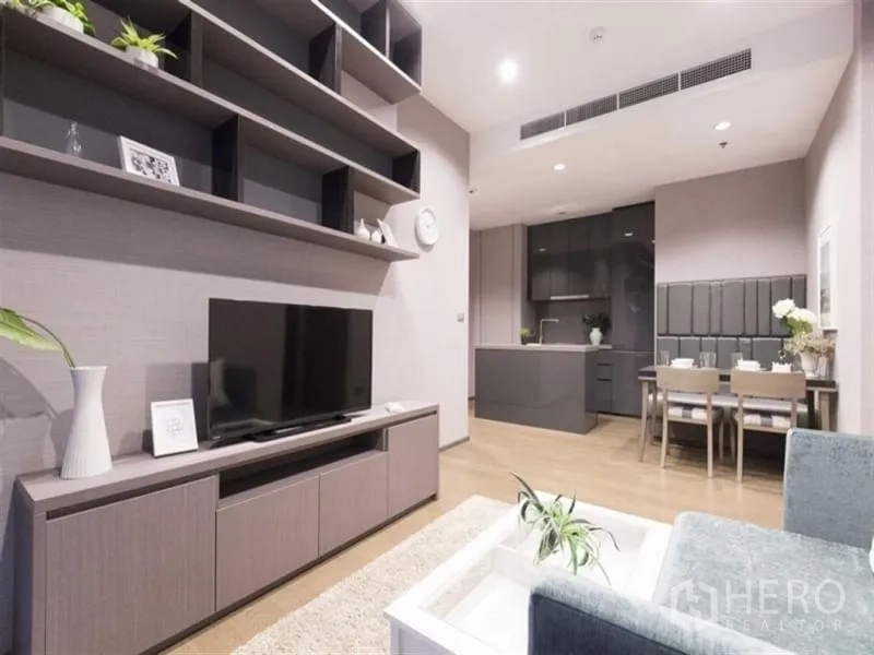 公寓 出租在Bang Rak, Bangkok - 客厅电视墙与层架，视野延伸至厨房与用餐区。