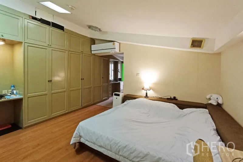 คอนโด ขายในBangkok - ห้องนอนแขกพร้อมตู้บิวท์อินเต็มผนัง เครื่องปรับอากาศ และแสงอบอุ่น