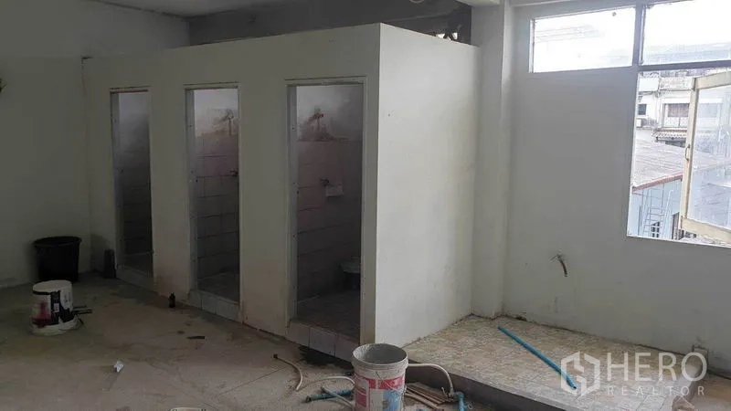 Shophouse for rent in Phra Khanong, Bangkok - Upper-floor area with three bathroom cubicles under renovation and a window for ventilation.
