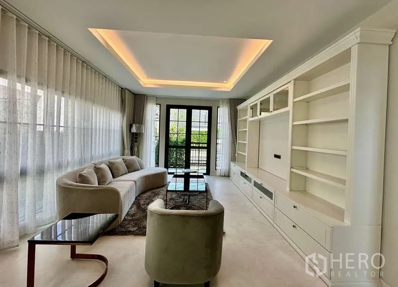 独立式住宅 出租在Bang Phli, Samut Prakan - 客厅灯槽天花，玻璃门通向庭院，软装舒适。
