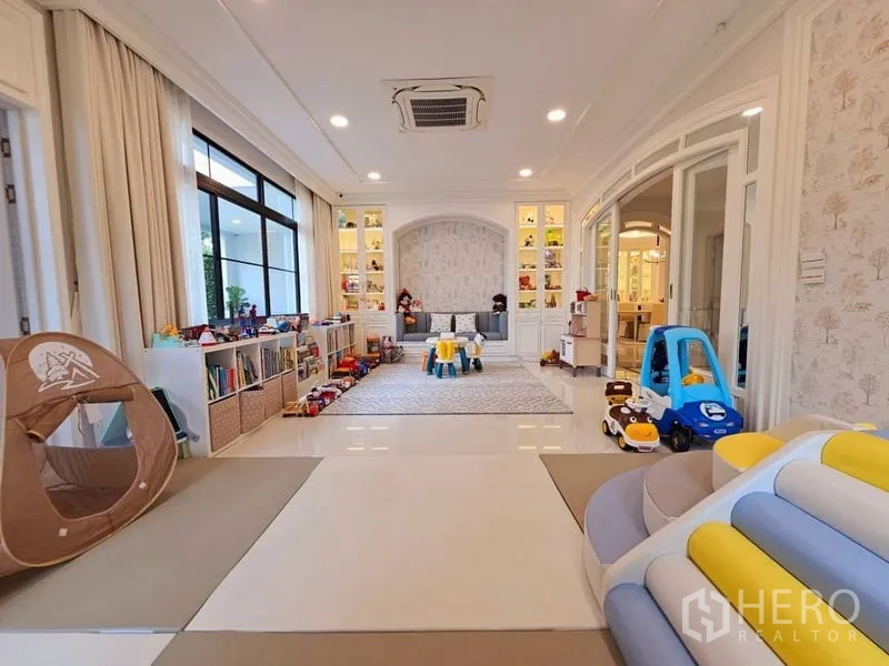 Detached House for rent or sale in Saphan Sung, Bangkok - Large children’s playroom with toys, open shelving and cushioned flooring beside sliding glass doors.