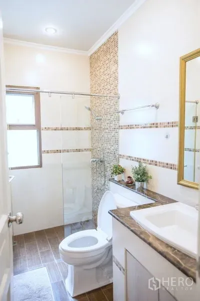 Detached House for sale in Lat Krabang, Bangkok - Compact bathroom with glass shower enclosure, vanity and window with neutral tiles.