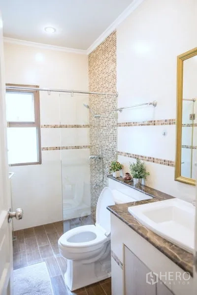 Detached House for sale in Lat Krabang, Bangkok - Compact bathroom with glass shower enclosure, vanity and window with neutral tiles.